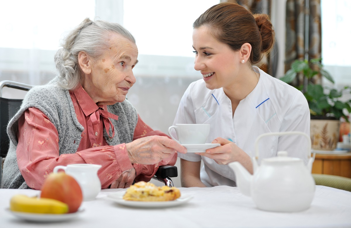 Verzorgende en oudere dame met koffie