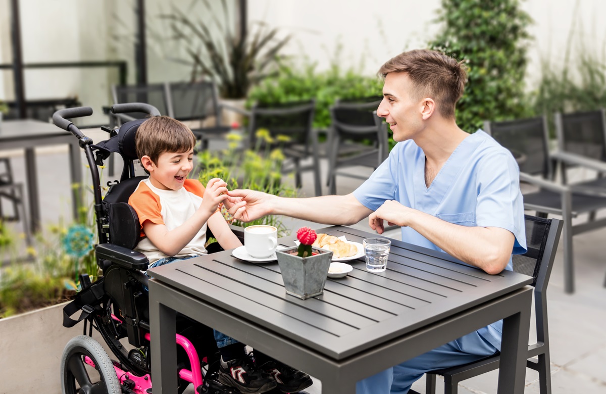 Verzorger met gehandicapt jongetje met eten